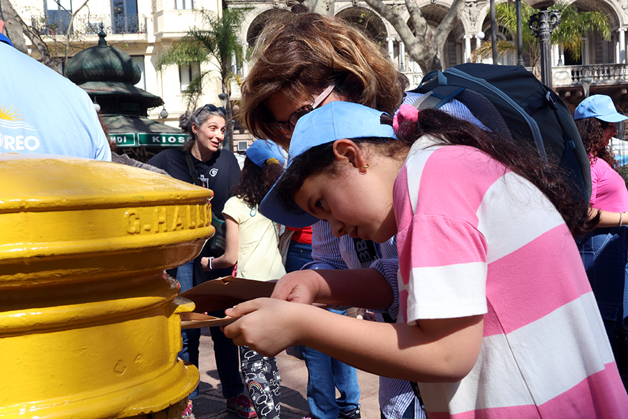 Niña deposita su postal en el antiguo buzón