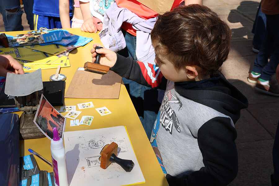 Un niño matasella el sobre donde viajará su postal